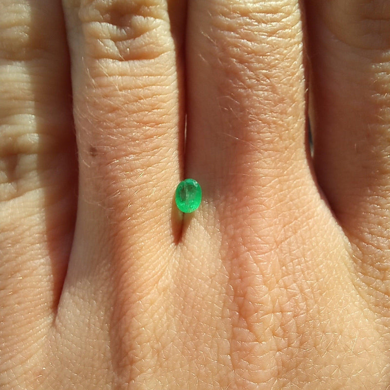 3.3mmx4.3mm Oval Emerald Stone with finger view - cape diamond exchange